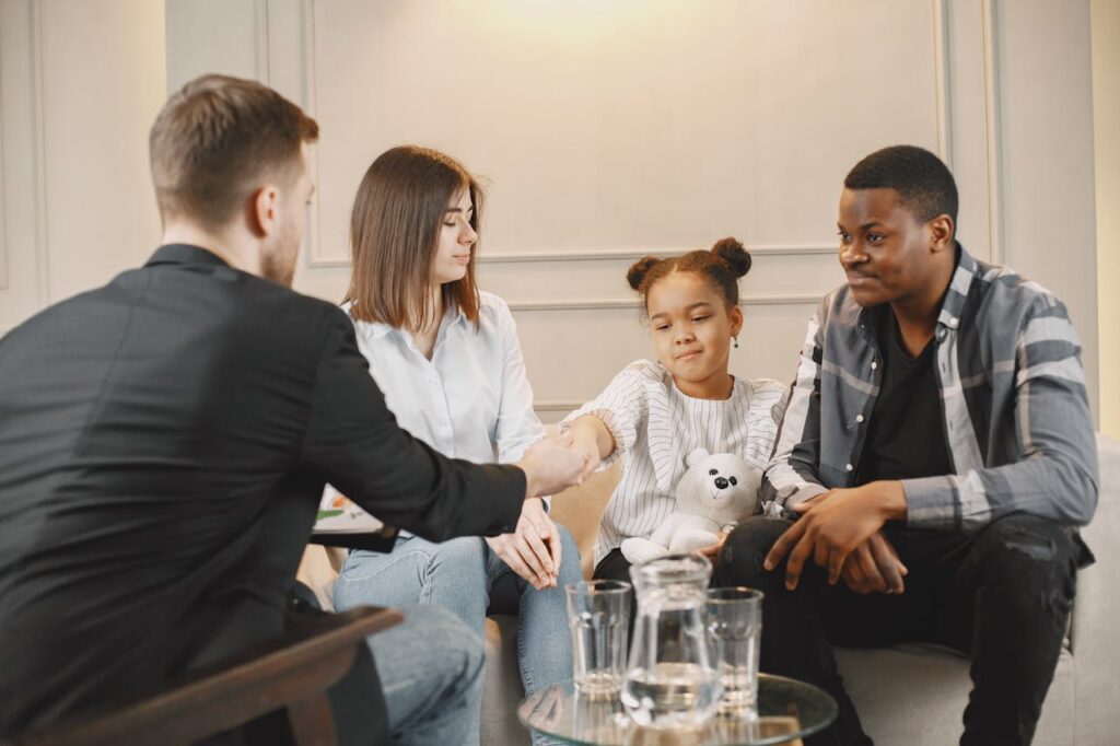 A family in a thoughtful counselling session with a professional in a modern setting.